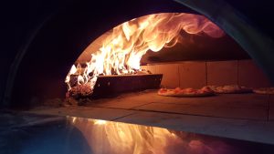 Pizza in brandende Clementi oven